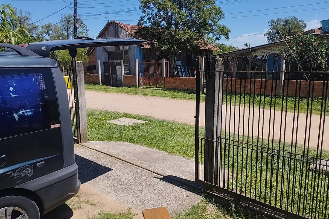 Veículo saindo de garagem com portão eletrônico deslizante de grades de ferro automatizado após manutenção.